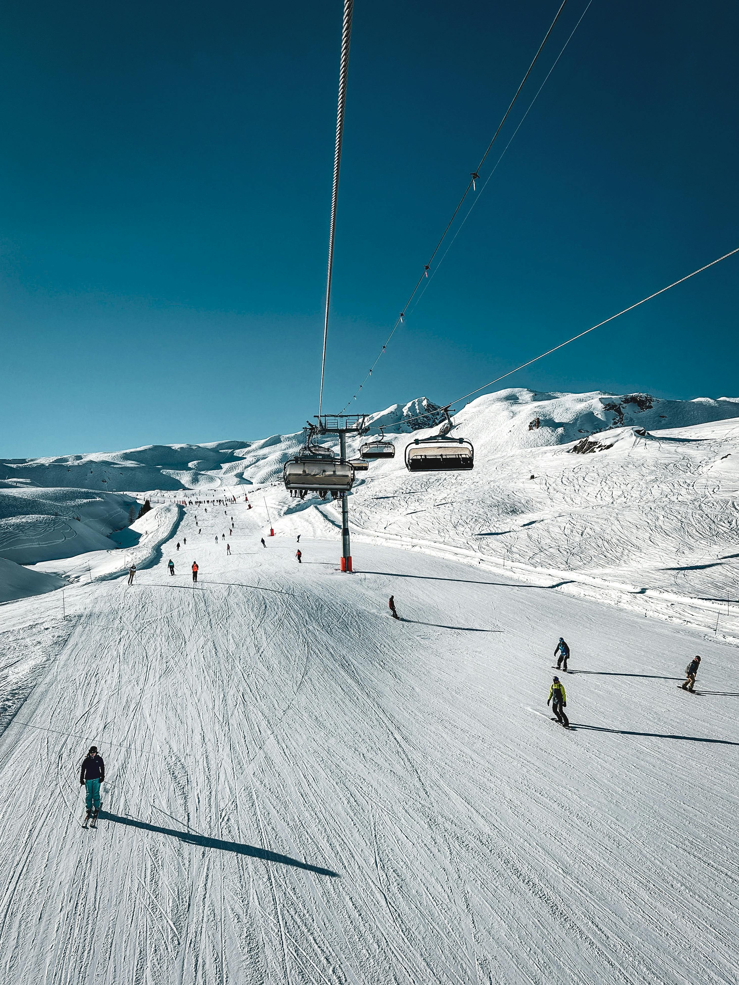 Skiers on a wide groomed piste with chairlift in Les Arcs ski area, Paradiski, French Alps